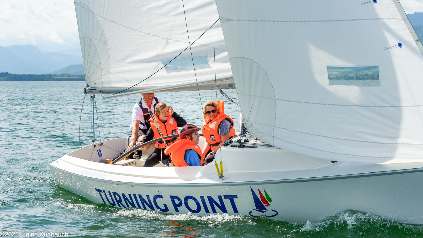 People are sitting in a sailing boat. They are sailing.