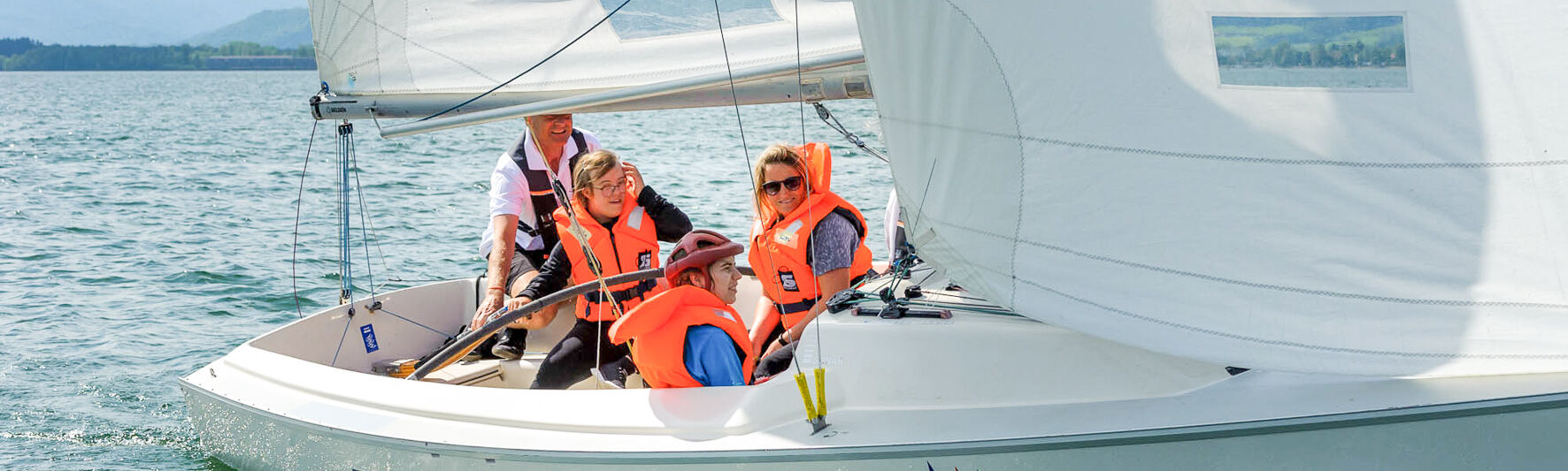 People are sitting in a sailing boat. They are sailing.