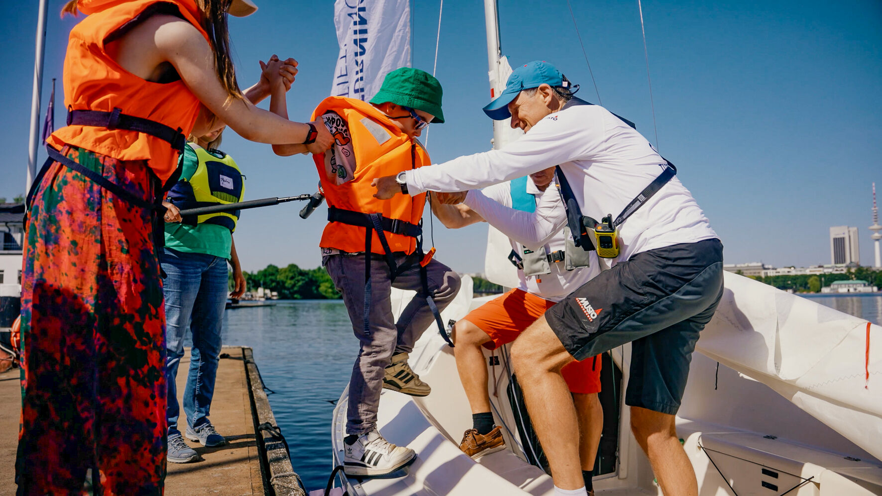 Ein Kind steigt vom Steg in ein Segelboot