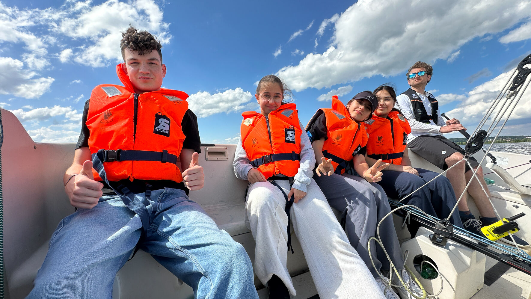 Teilnehmende sitzen in einem Boot. Alle haben Rettungswesten an.
